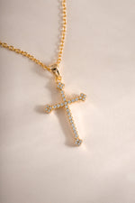 Close-up of a gold cross pendant necklace from Sami Jewels, showcasing detailed craftsmanship and elegant jewelry design.