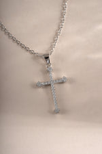 Close-up of a sterling silver cross pendant necklace by Sami Jewels, showing detailed craftsmanship on a sleek necklace chain.