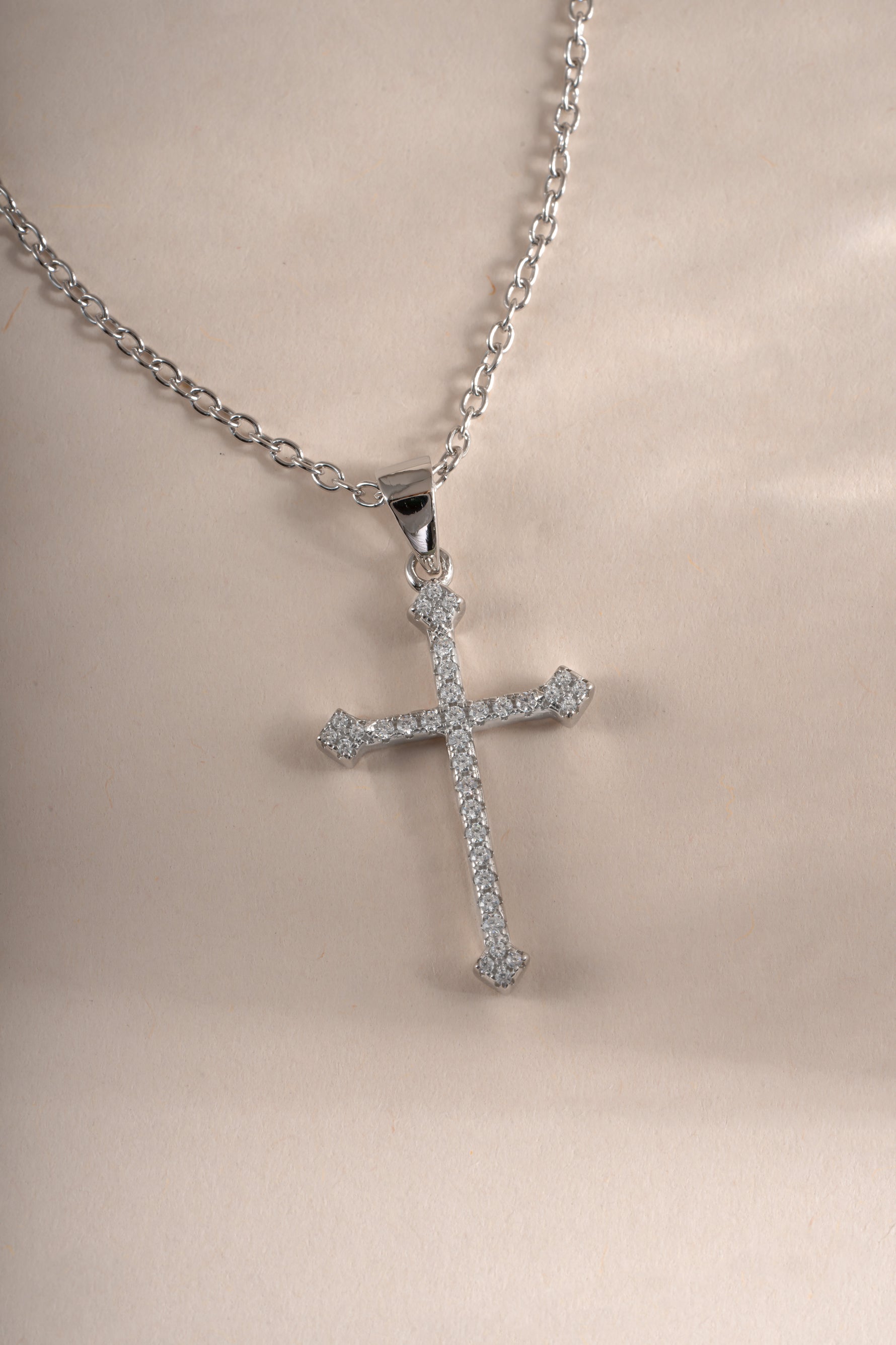 Close-up of a sterling silver cross pendant necklace by Sami Jewels, showing detailed craftsmanship on a sleek necklace chain.