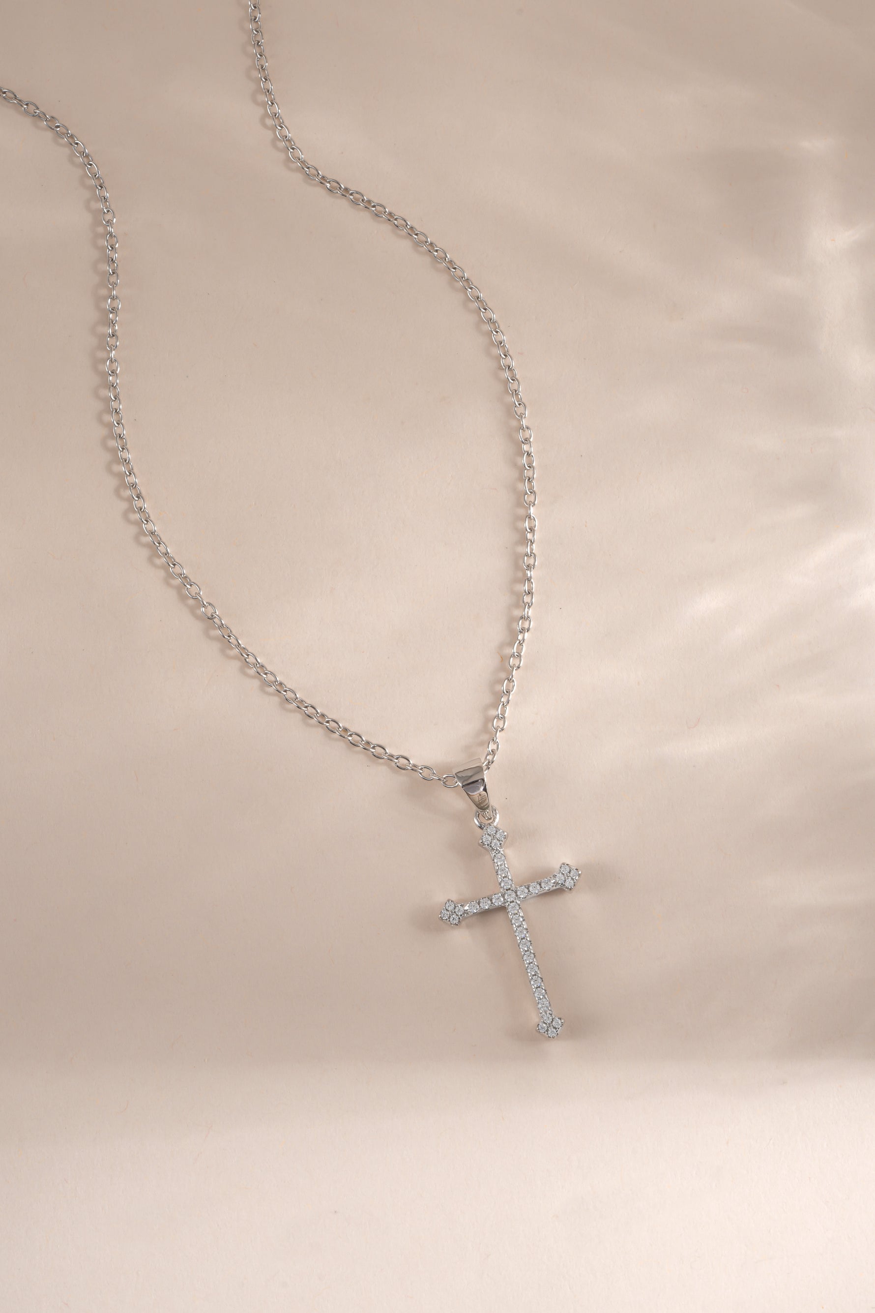 Sterling silver cross pendant necklace from Sami Jewels displayed flat, showcasing its sleek design and polished finish.