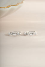 Sterling silver CZ baguette huggie earrings shown from the side, featuring sparkling baguette-cut cubic zirconia stones.