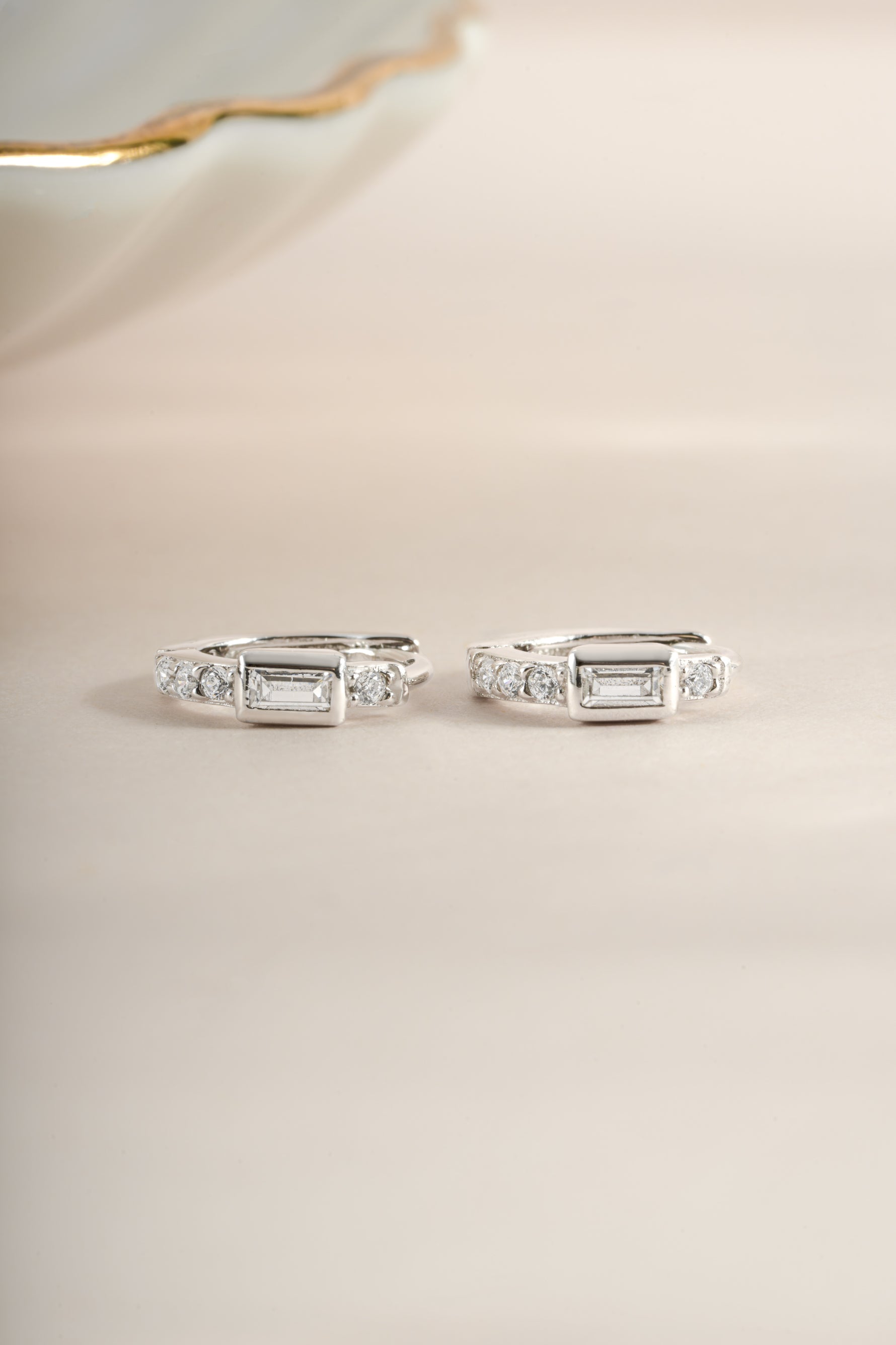 Sterling silver CZ baguette huggie earrings shown from the side, featuring sparkling baguette-cut cubic zirconia stones.