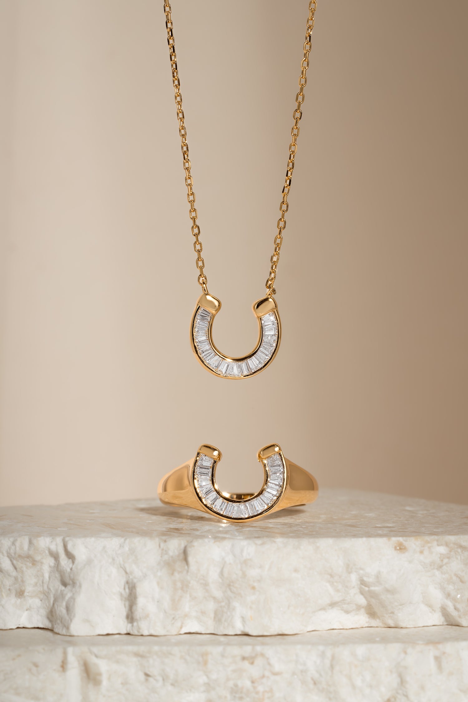 Gold horseshoe jewelry set including a necklace and ring with cubic zirconia details from Sami Jewels.