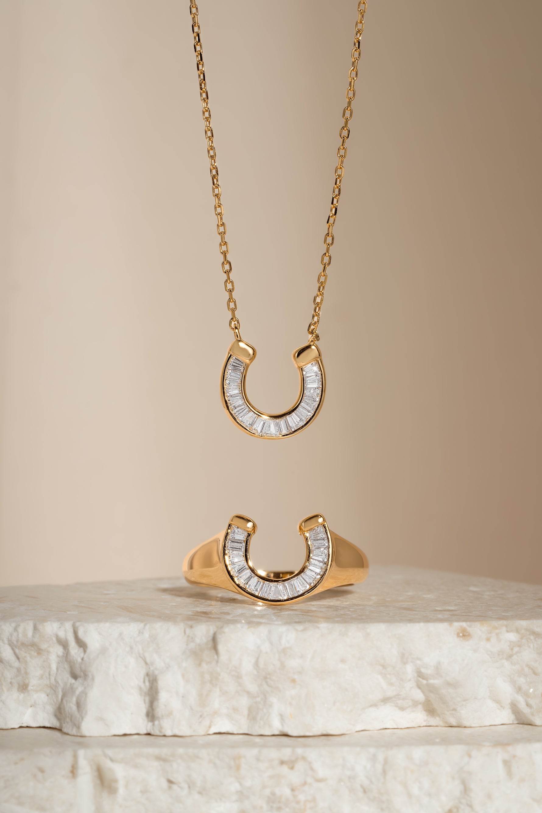 Gold horseshoe jewelry set including a necklace and ring with cubic zirconia details from Sami Jewels.