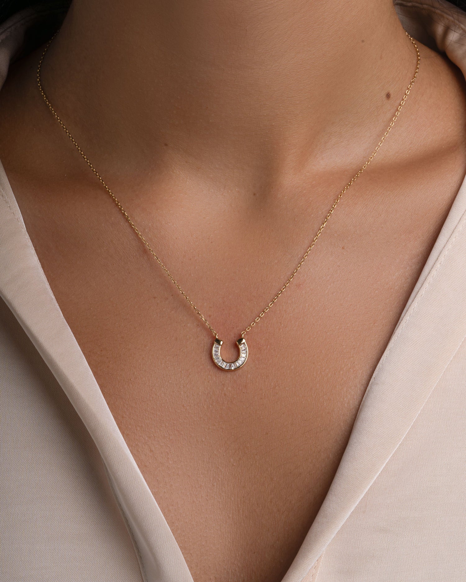 Gold horseshoe pendant necklace from Sami Jewels featuring sparkling cubic zirconia stones, jewelry accessory for good luck.