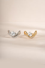 Close-up side by side image of gold and silver wavy oval diamond ring sets with pavé bands. 