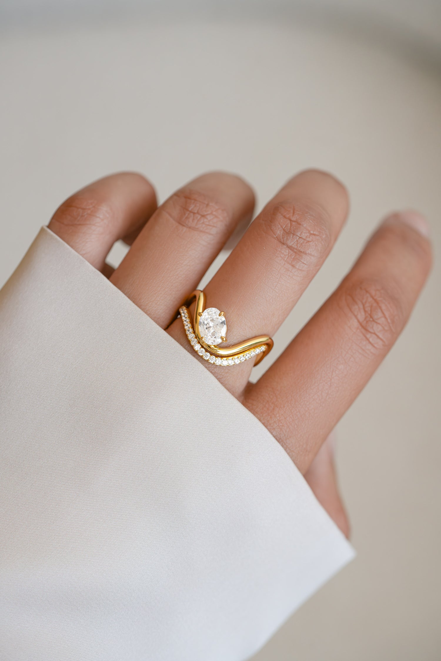 Model wearing a gold statement cz wedding ring set with oval diamond. 