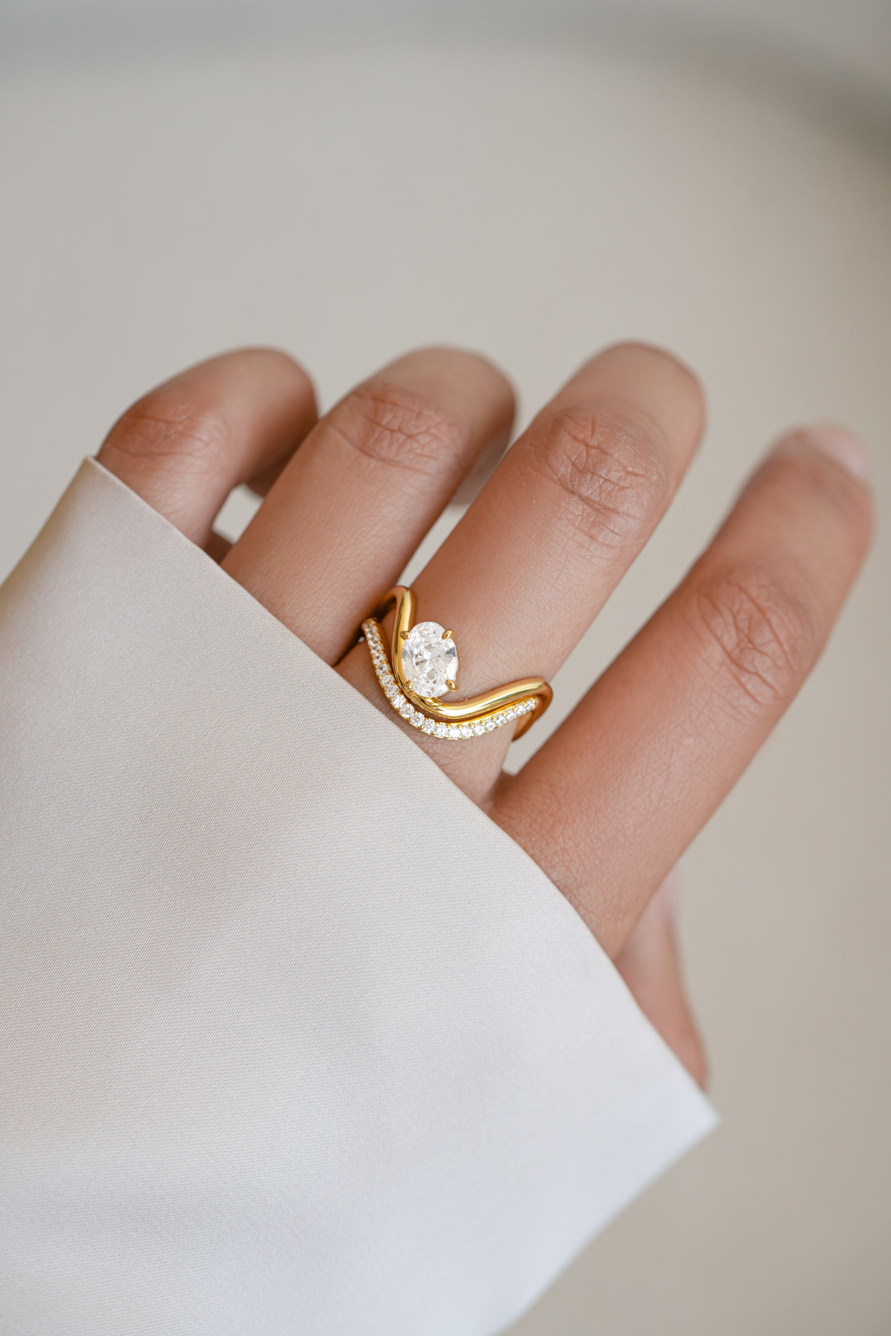 Model wearing a gold statement cz wedding ring set with oval diamond. 