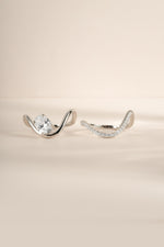 Close-up product image of silver oval diamond wavy ring set, showing both rings in the set side by side. 