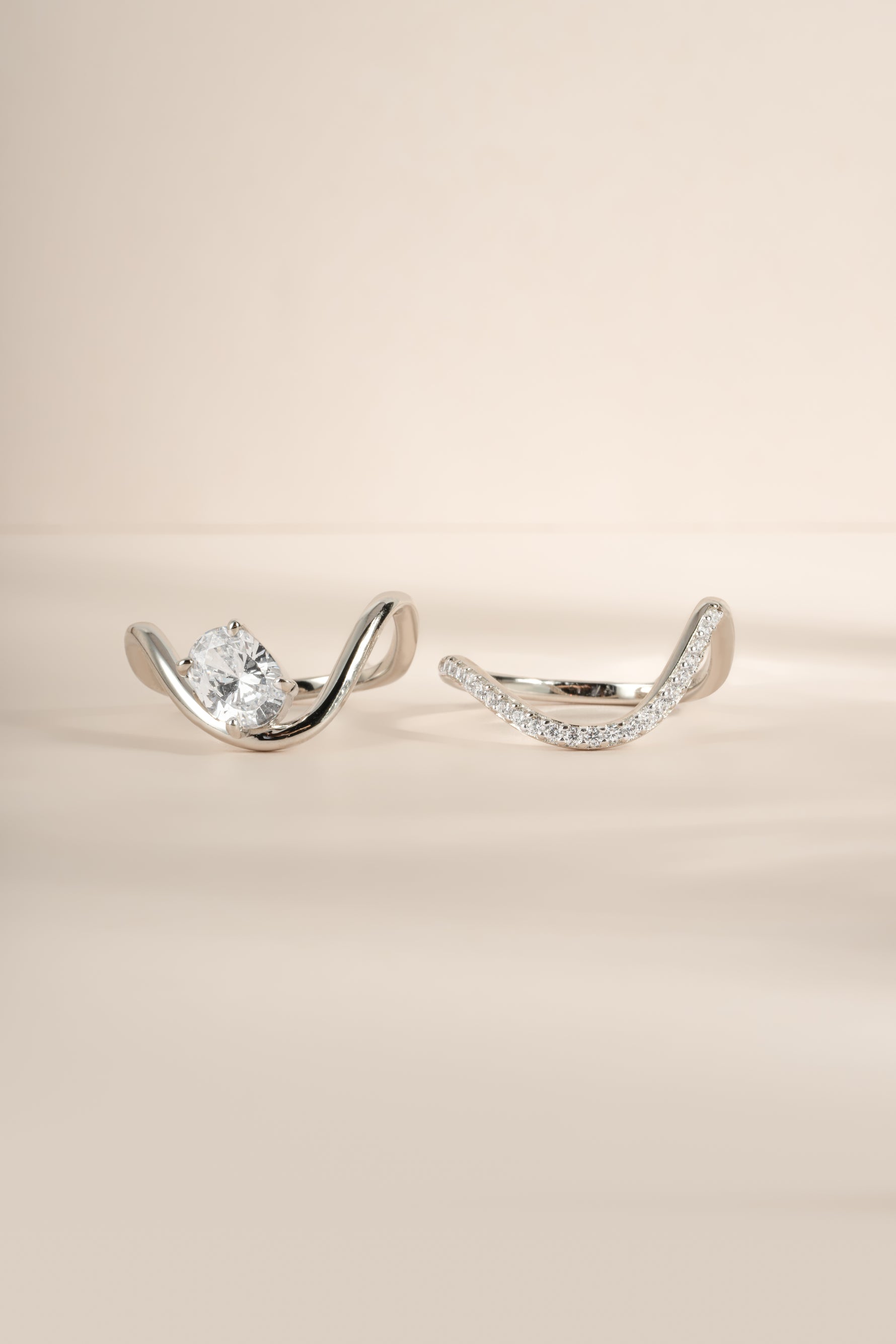 Close-up product image of silver oval diamond wavy ring set, showing both rings in the set side by side. 