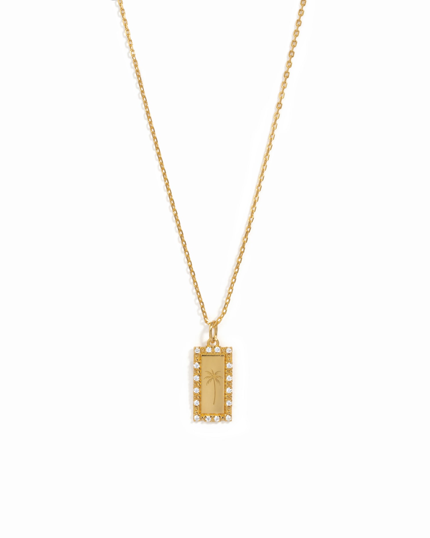 Gold necklace with a palm tree engraved medallion pendant on a white background