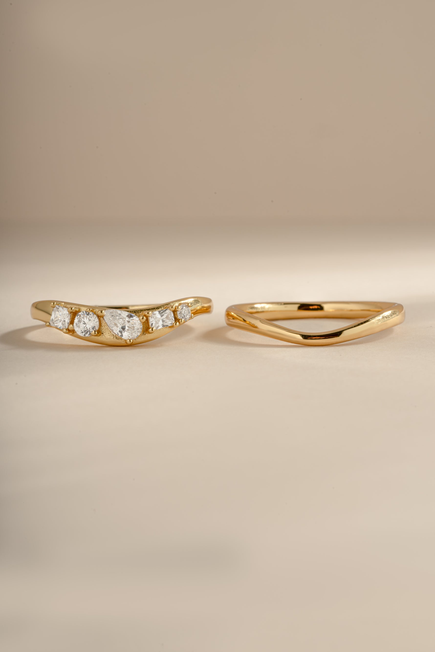 Up-close image of gold chevron ring set, showing both rings in the set, side by side. Left ring features 5 cz stones and right ring is plain gold. 