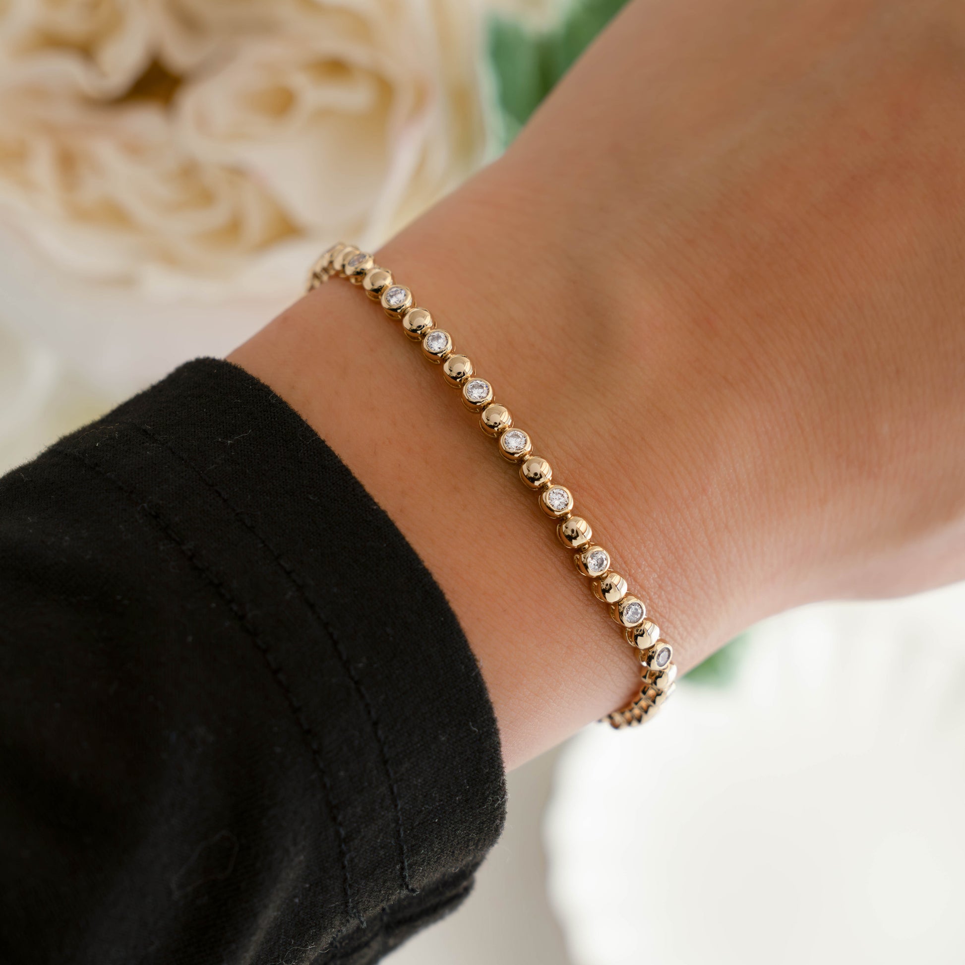 Gold beaded cz tennis bracelet worn on woman's wrist