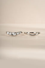Up-close image of silver wavy ring set, showing both rings in the set, side by side. Left ring features 5 cz stones and right ring is plain gold. 