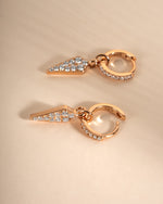 Gold Dagger Charm Huggies earrings by Sami Jewels featuring close-up view of small, stylish hoop earrings with dagger charms.