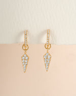 Gold dagger charm huggie earrings by Sami Jewels featuring small hoop style earrings with dagger-shaped pendants.
