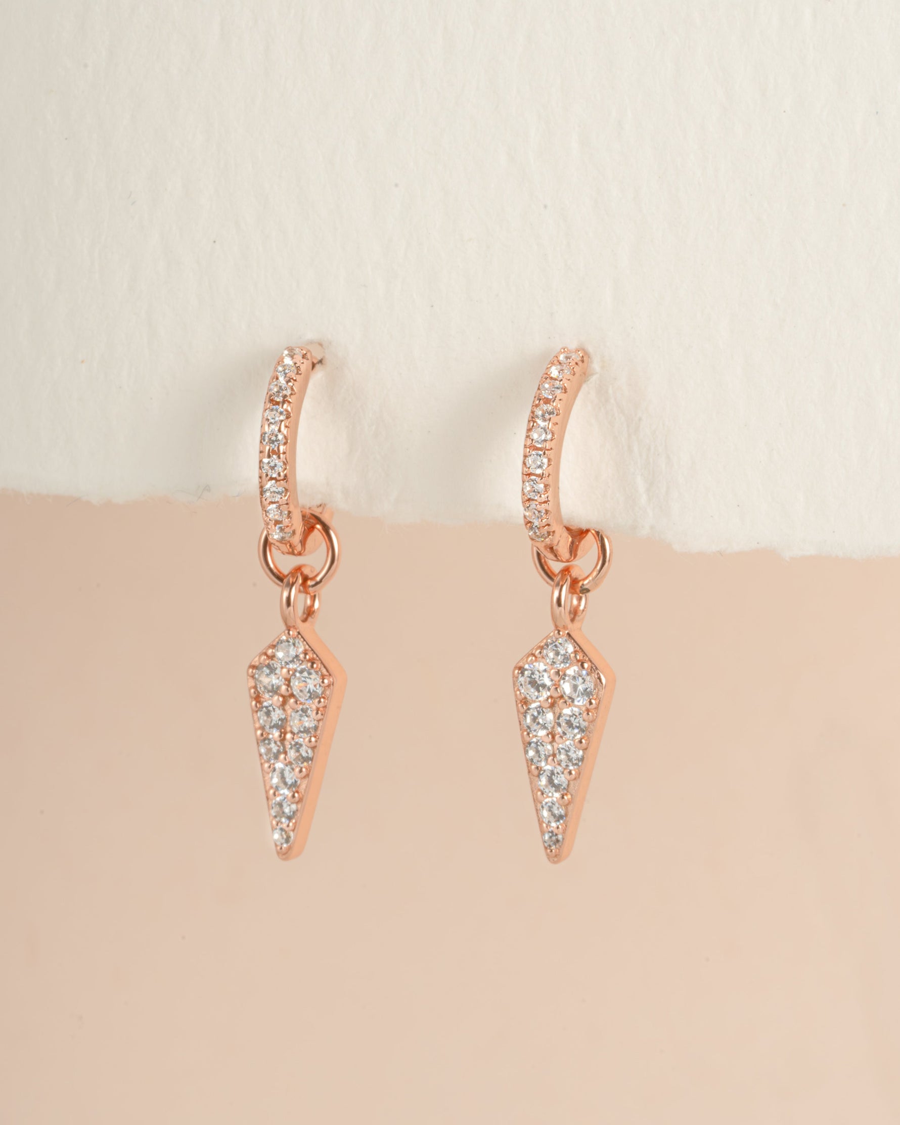 Rose gold Dagger Charm Huggie earrings by Sami Jewels, close-up view showing detailed dagger charms on small hoop earrings.