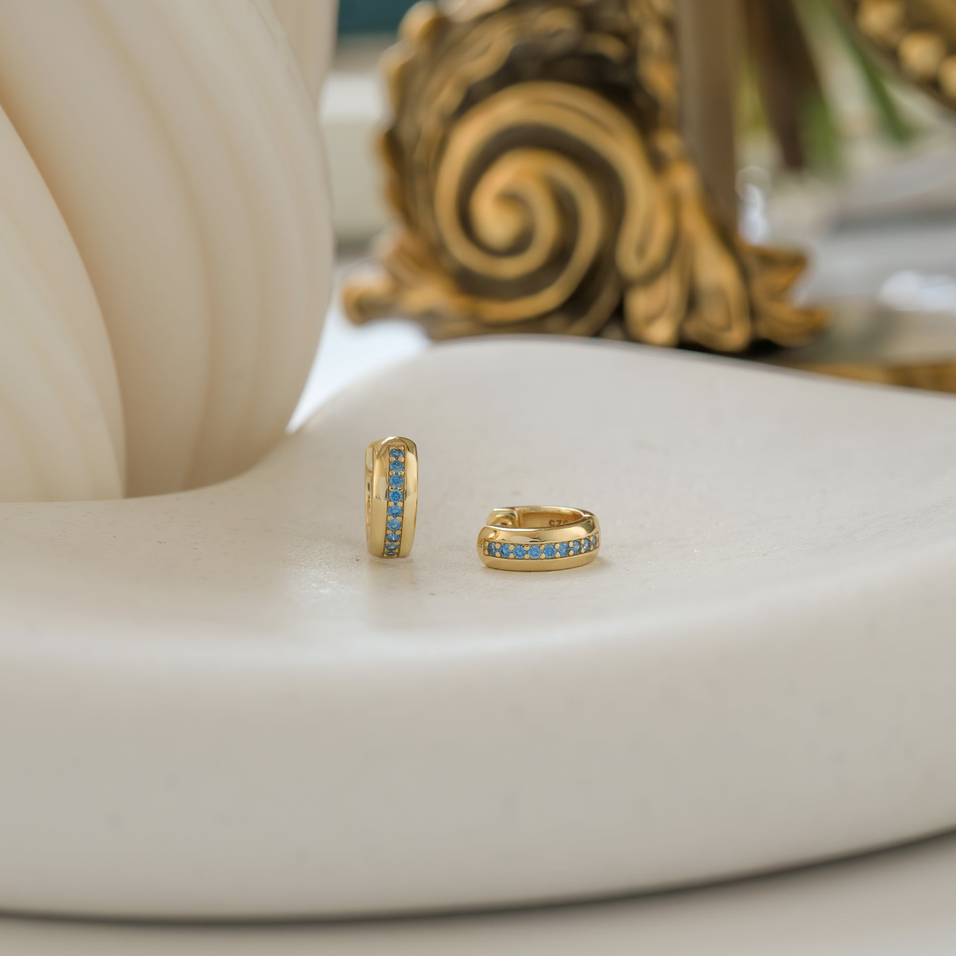 a pair of small gold hoop earrings with aquamarine stones