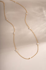 Dainty beaded pearl necklace by Sami Jewels featuring small pearls on a delicate gold chain, laid flat for display.