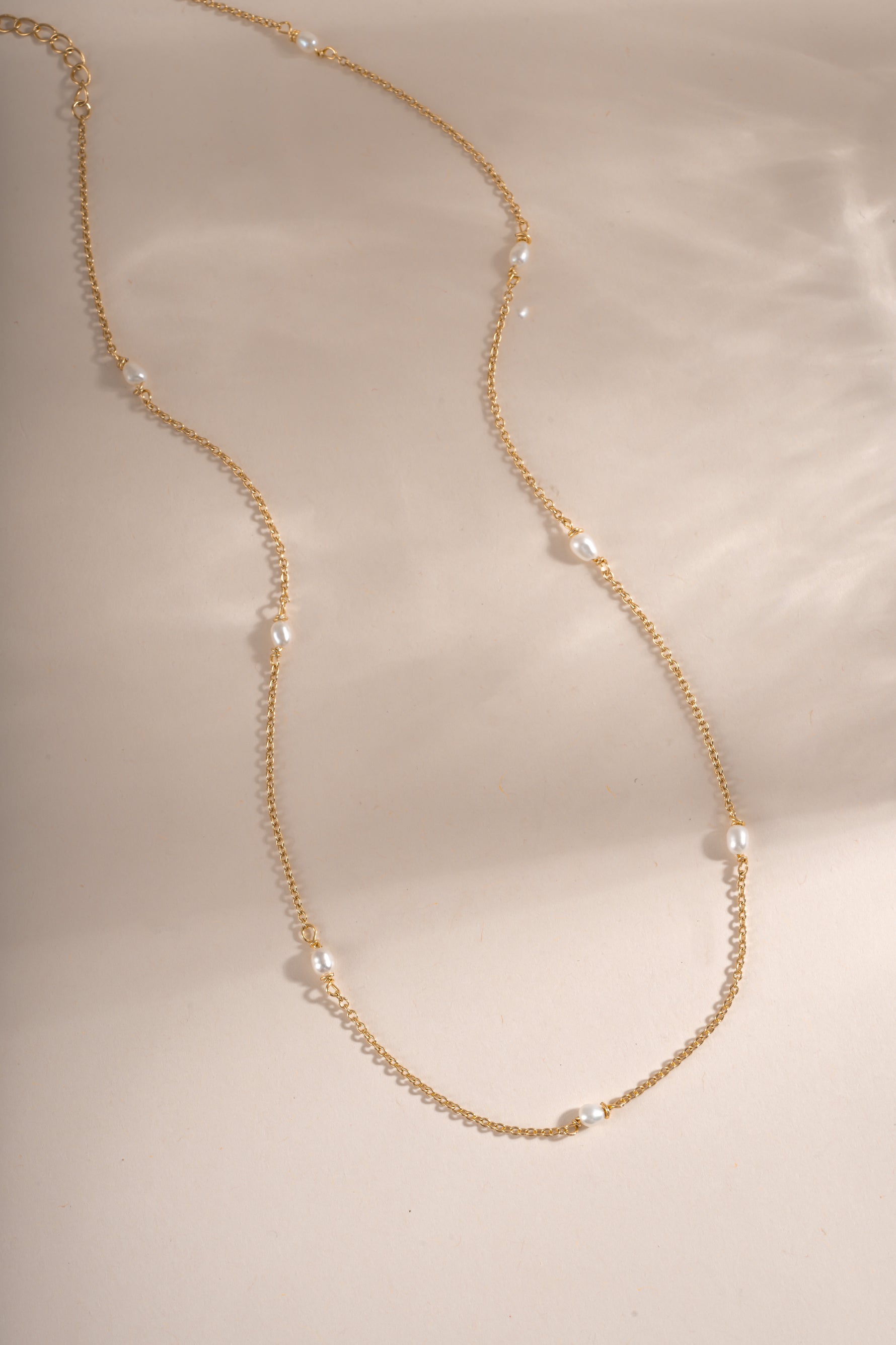 Dainty beaded pearl necklace by Sami Jewels featuring small pearls on a delicate gold chain, laid flat for display.