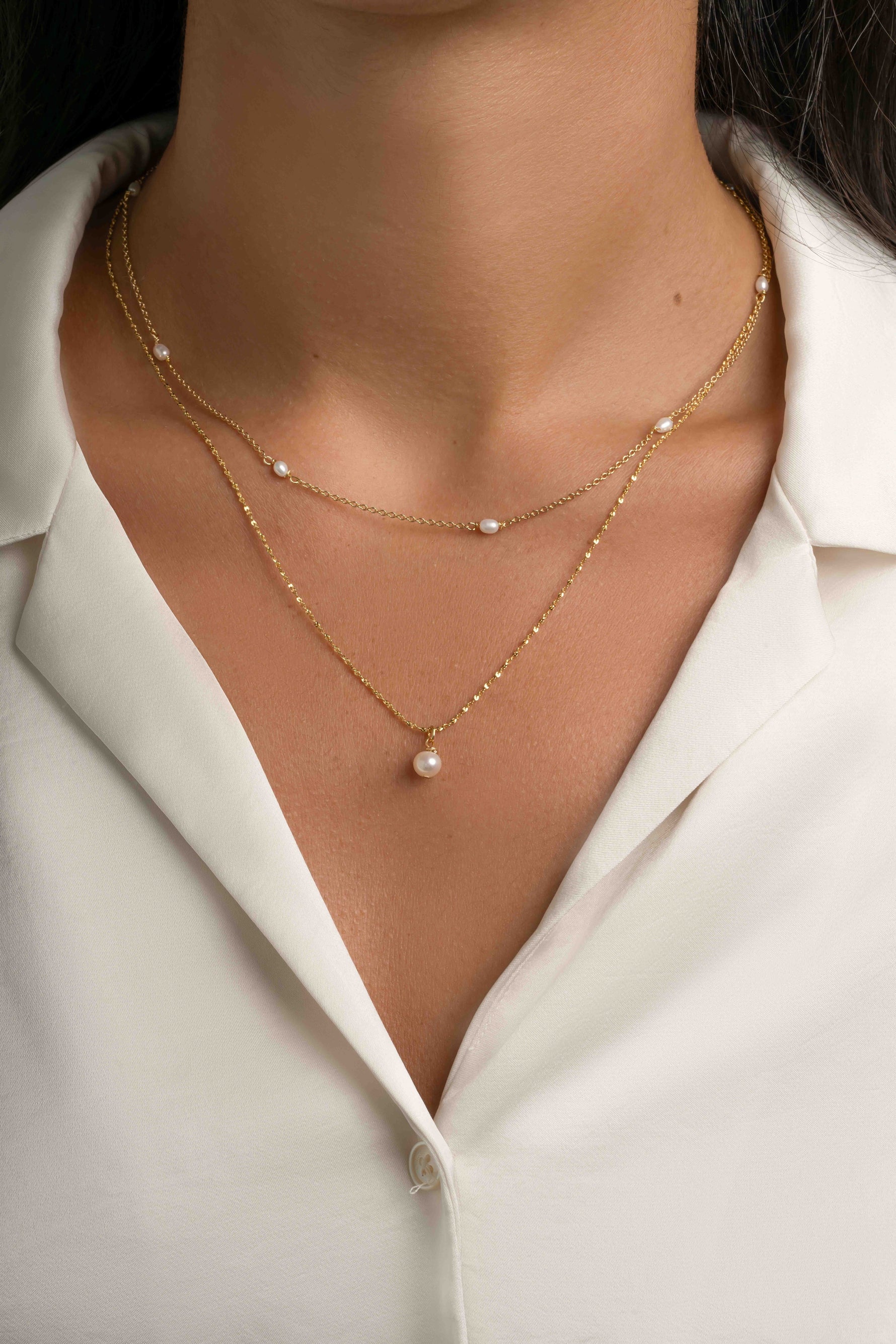 Dainty beaded pearl necklace by Sami Jewels, featuring small pearls on a delicate gold chain, worn layered on a model.