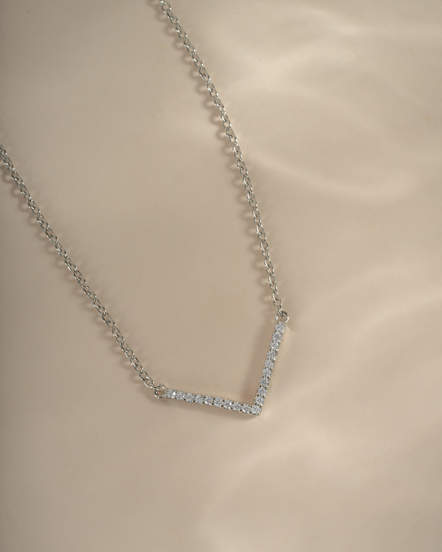 Close-up of a sterling silver chevron necklace from Sami Jewels, showcasing a delicate, dainty pendant on a fine chain.