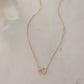 Delicate 14k gold plated love link necklace on white marble background.