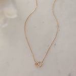 Delicate 14k gold plated love link necklace on white marble background.