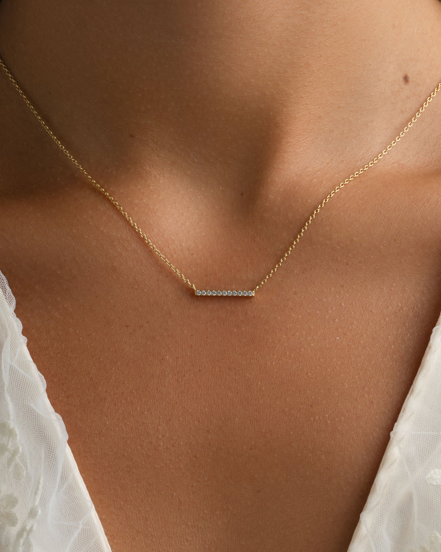 Gold dainty bar necklace with diamond accents from Sami Jewels worn by a model. Elegant jewelry accessory.