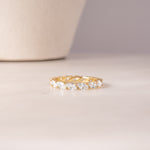 flat lay of a 14k gold ring highlighting its continuous row of sparkling gemstones set in gold, offering a mix of smooth and textured finishes.