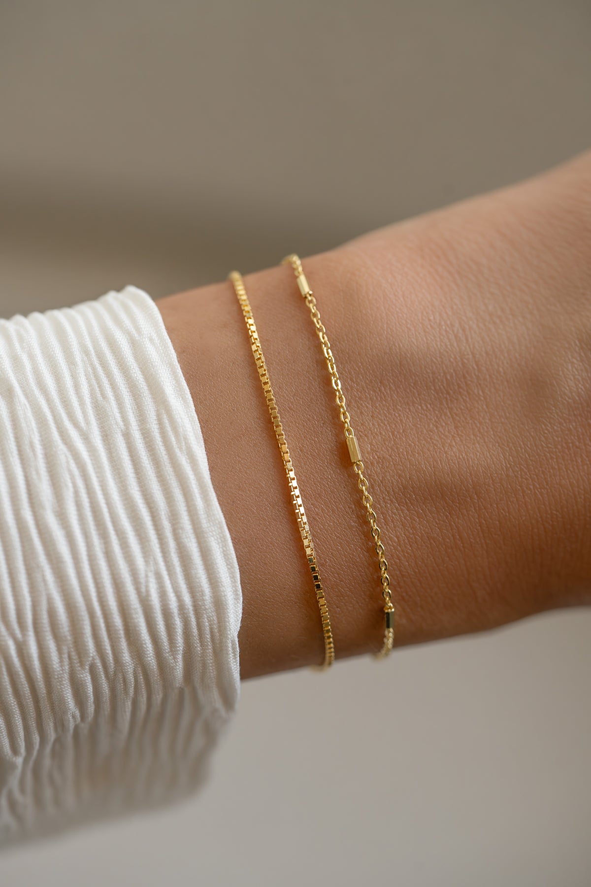 Dainty gold box chain bracelet set with satellite chain design, layered on a wrist, by Sami Jewels.