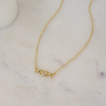 Close-up of a gold "MOM" necklace with a CZ heart, perfect for a Mother’s Day gift.