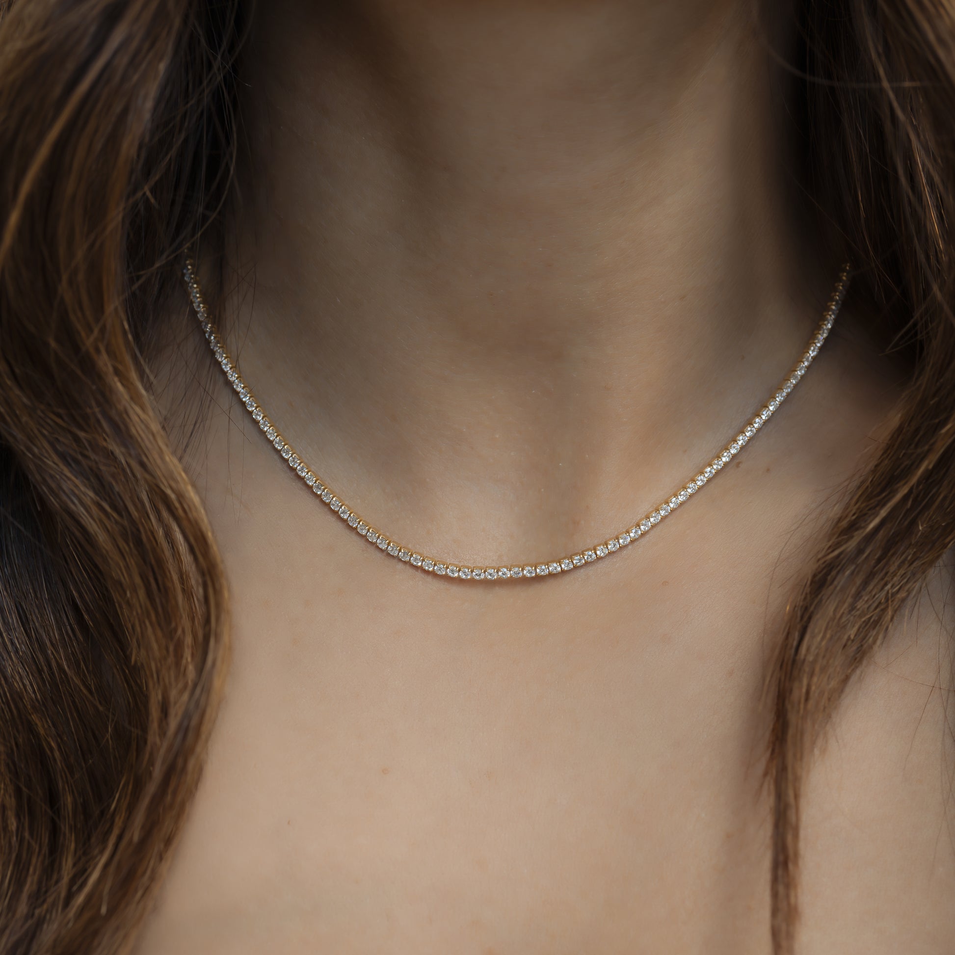 model wearing thin gold tennis necklace