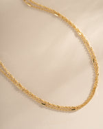 Close-up of Sami Jewels dainty gold layering necklace set, featuring multiple delicate necklaces on a neutral background.