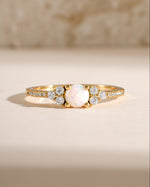 Dainty gold opal ring with a smooth, polished surface, featuring a central opal gemstone, showcasing elegant jewelry design.