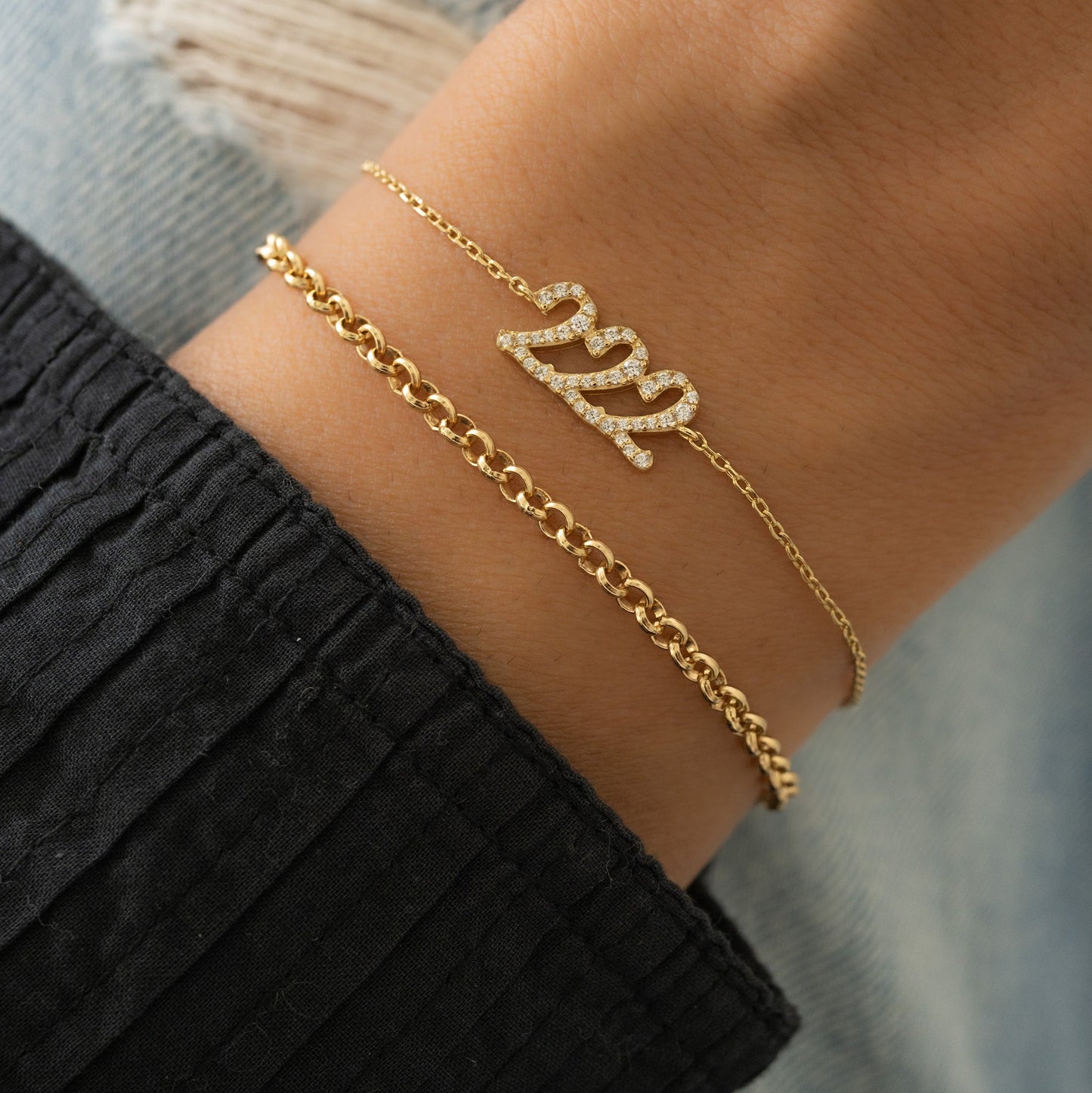 Angel Number Bracelet in gold stacked on wrist with a simple rolo chain bracelet