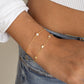 model wearing a dainty pearl bracelet and a minimalist star charm bracelet