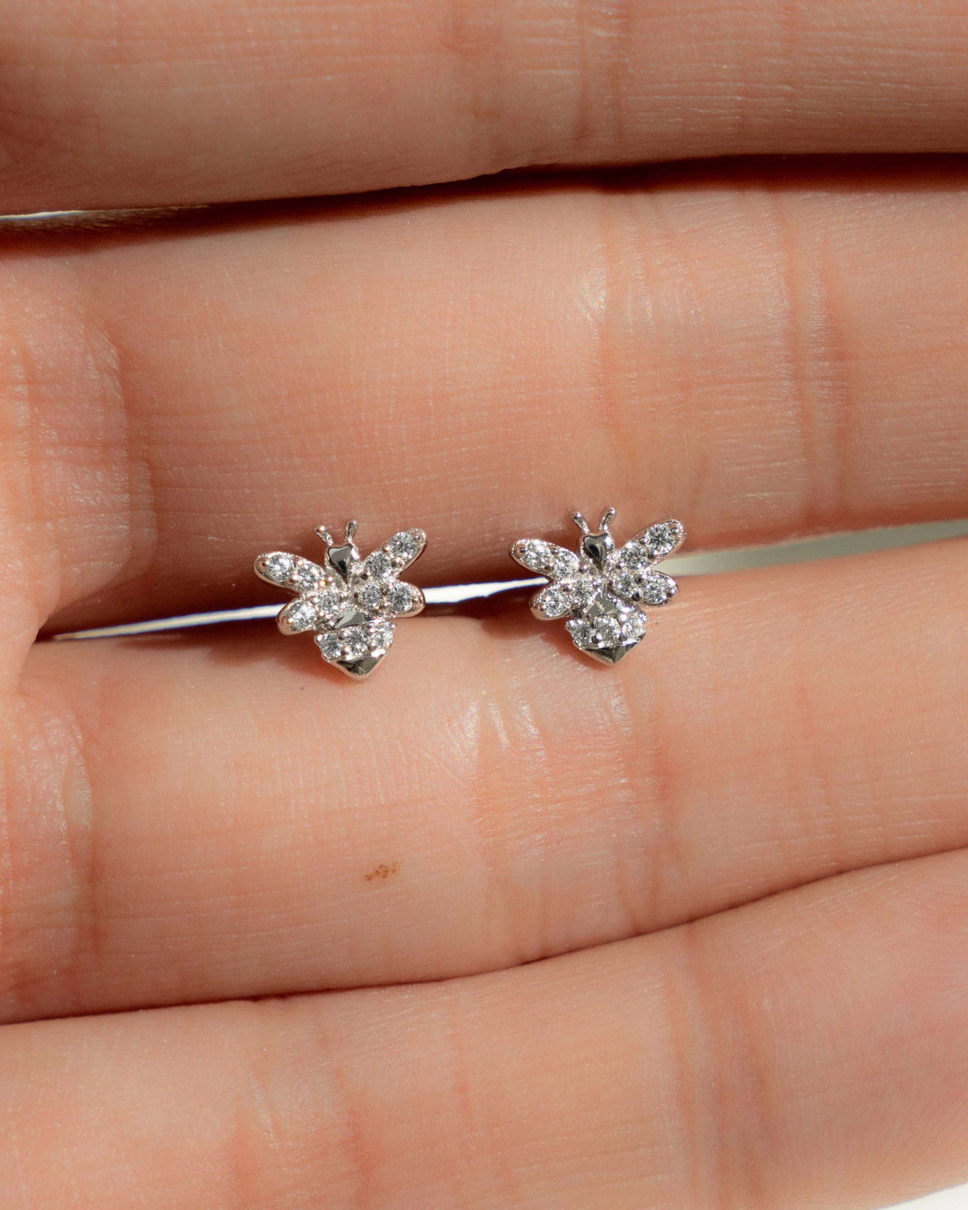 closeup image of silver stud earrings with a bee earring design