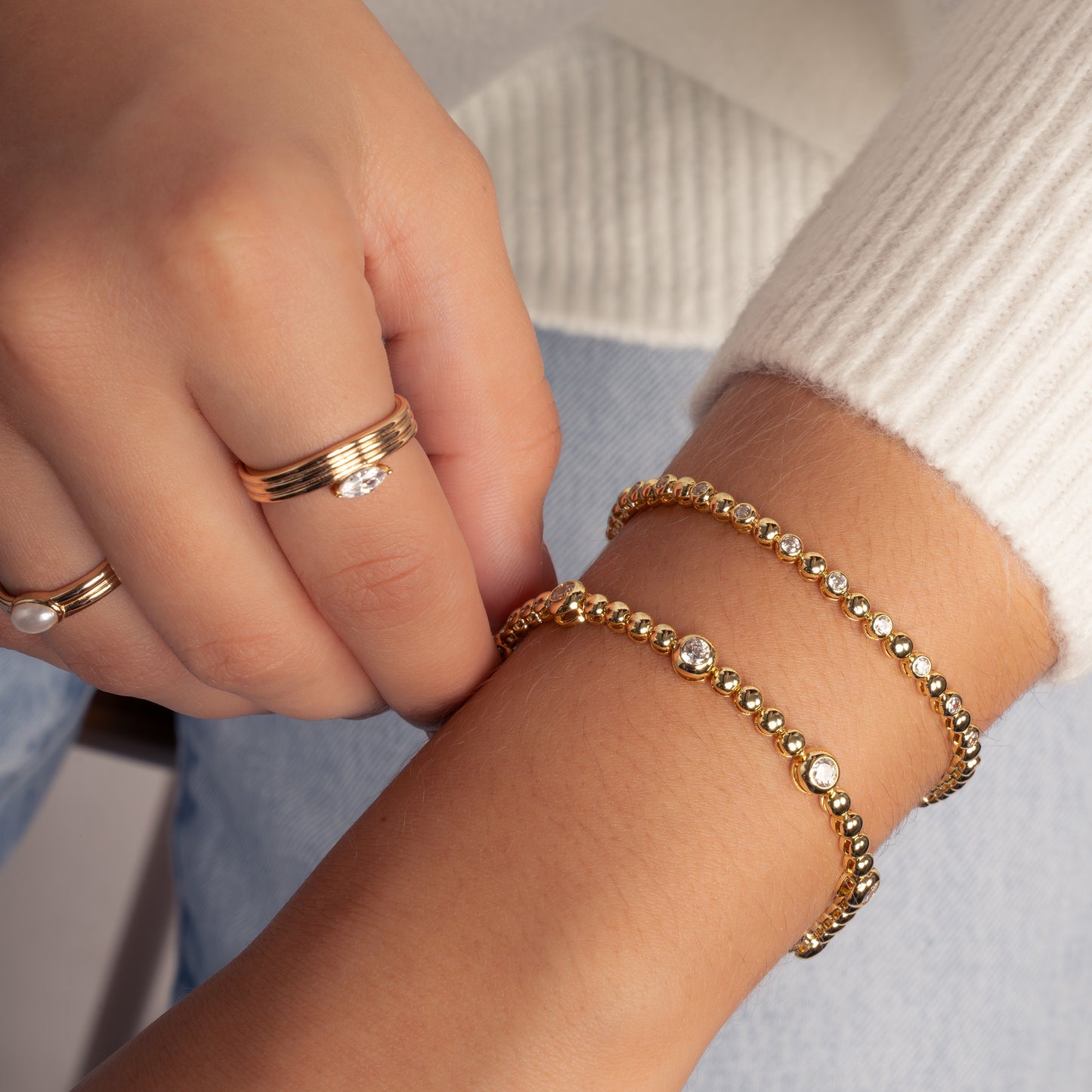 Woman wearing diamond gold plated tennis bracelets with round diamond bezel settings.