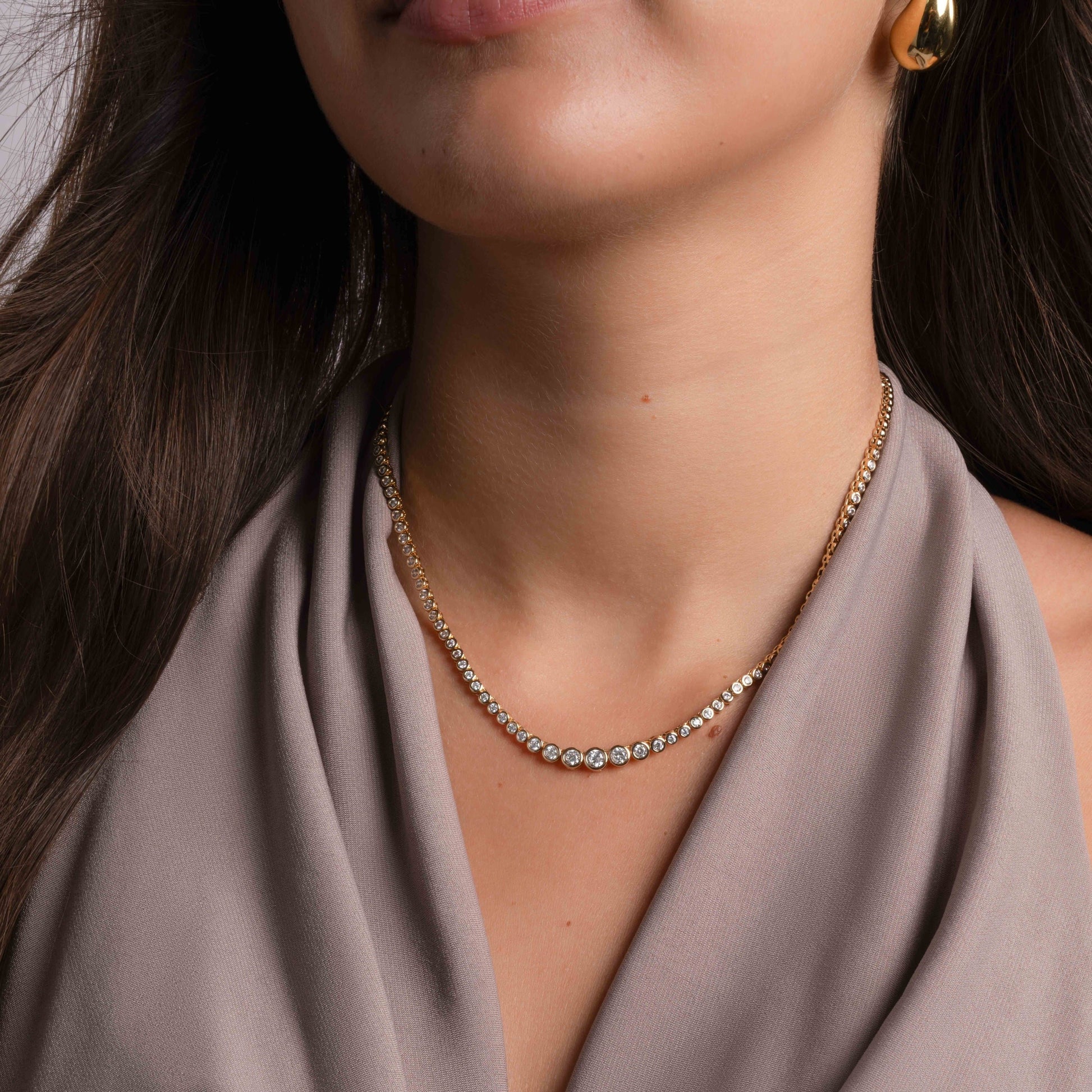 model wearing gold tennis necklace with diamond accents. 