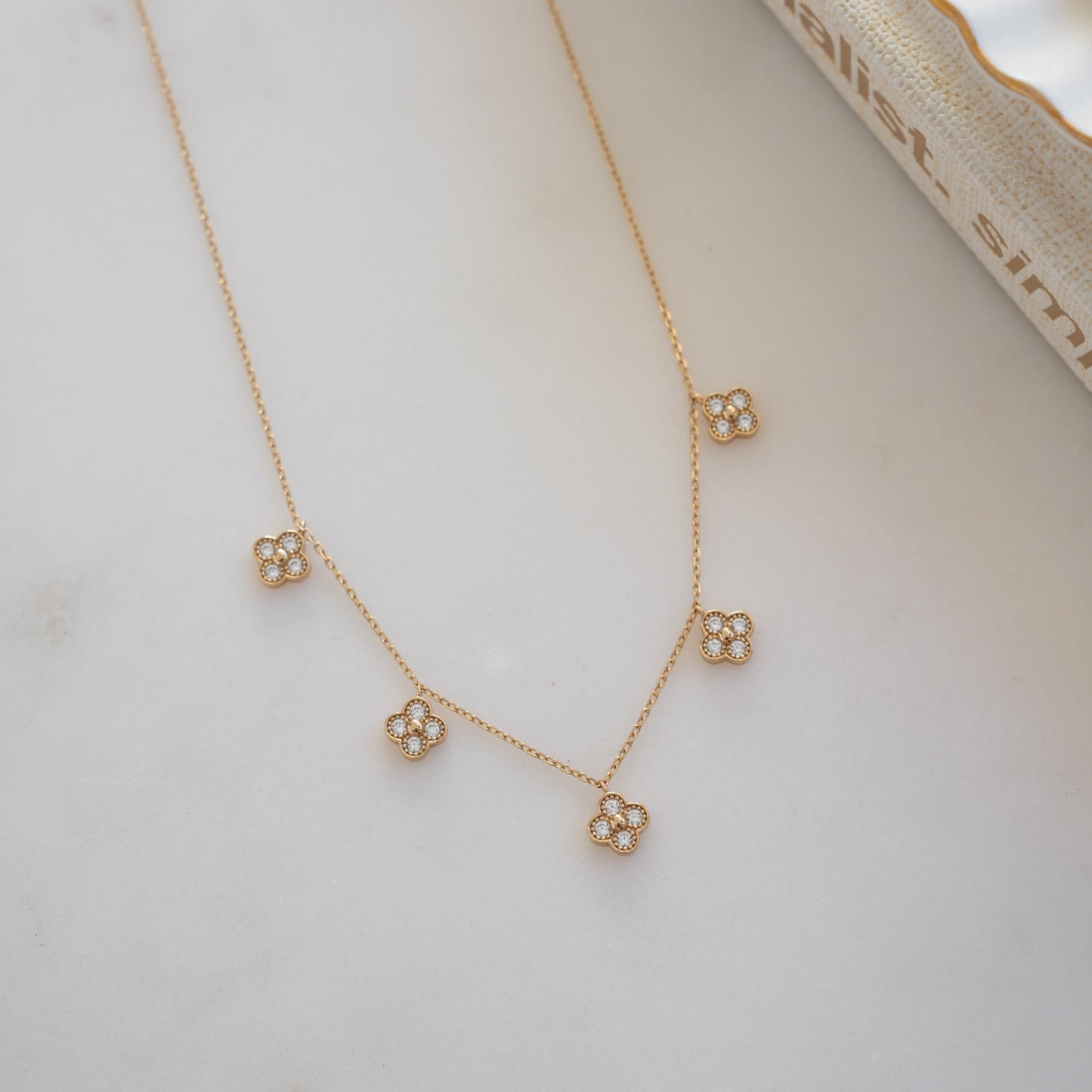 flat lay of a gold chain with  diamond-encrusted clover charms.