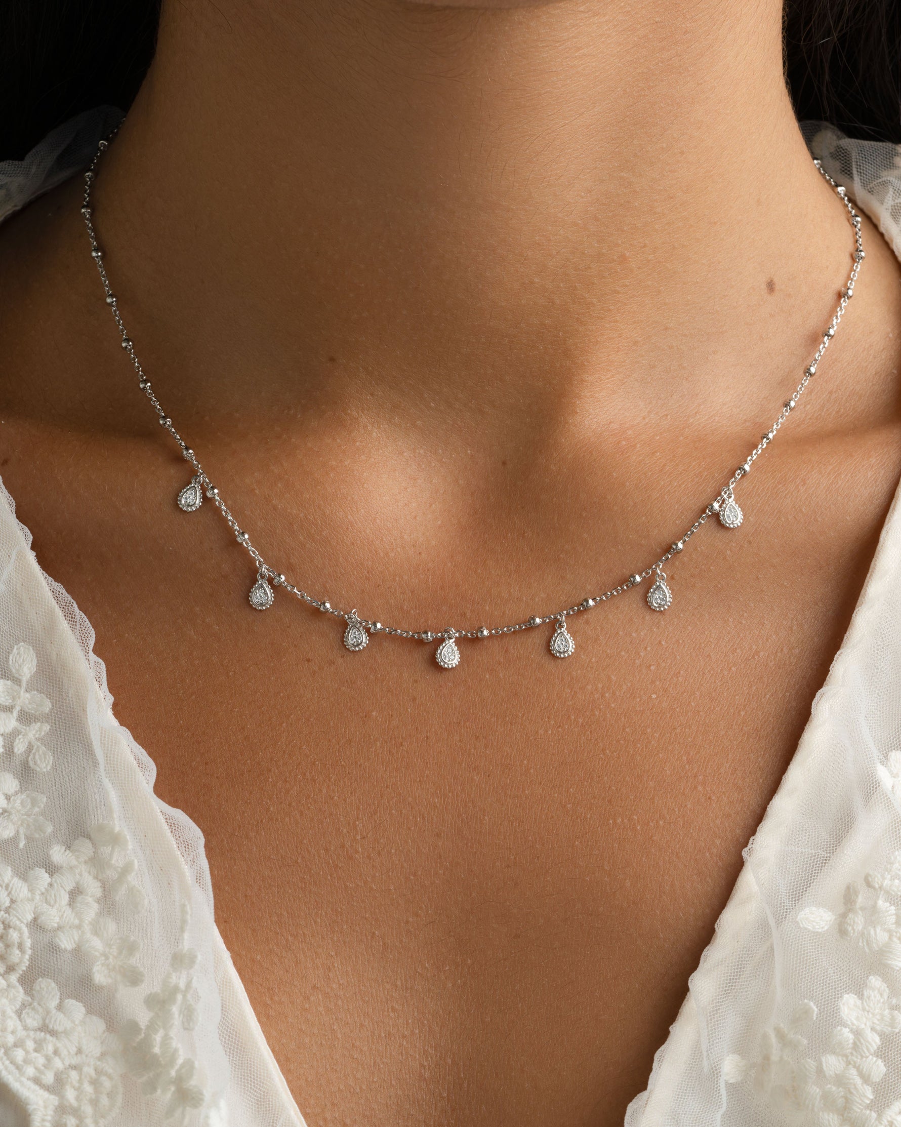 Sterling silver dangling teardrop necklace by Sami Jewels displayed on a model, showcasing elegant jewelry design.