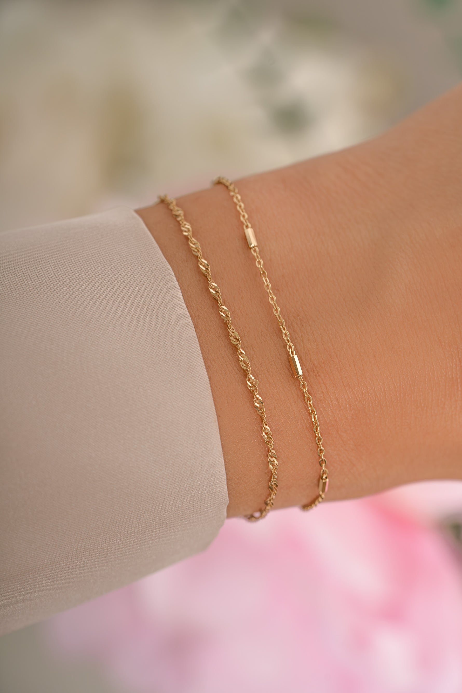 Gold delicate bracelet set by Sami Jewels, featuring layered thin bracelets on a model's wrist.