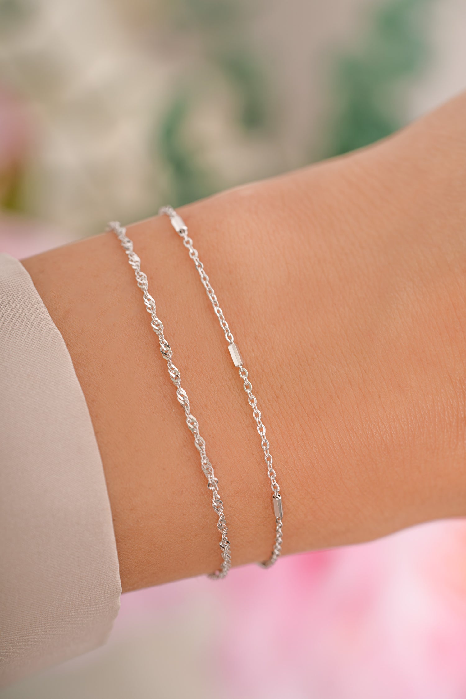 Delicate sterling silver bracelet set by Sami Jewels featuring thin, elegant bracelets on a model's wrist.