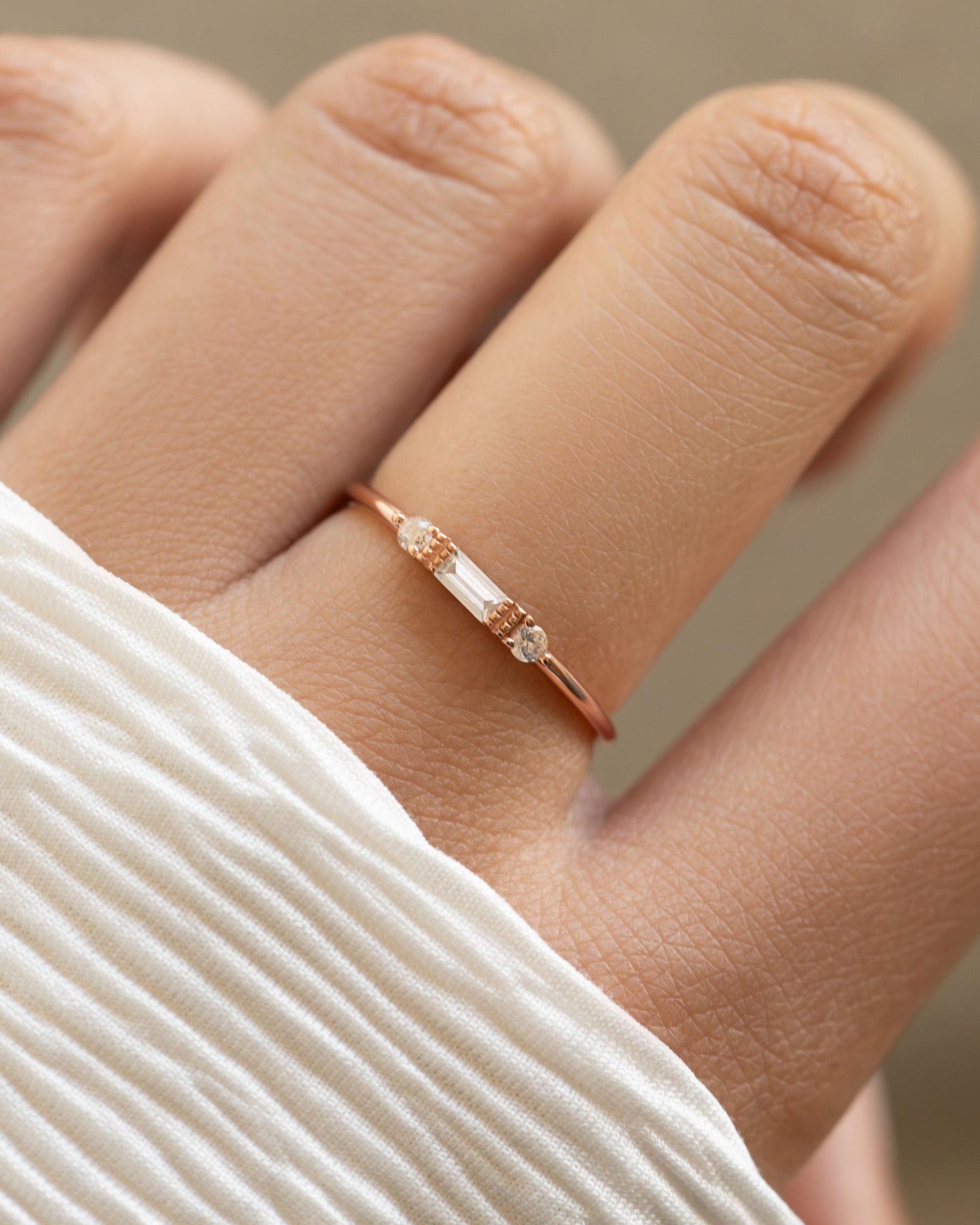 White CZ baguette ring by Sami Jewels featuring a sleek design with sparkling baguette-cut stones on a rose gold band.