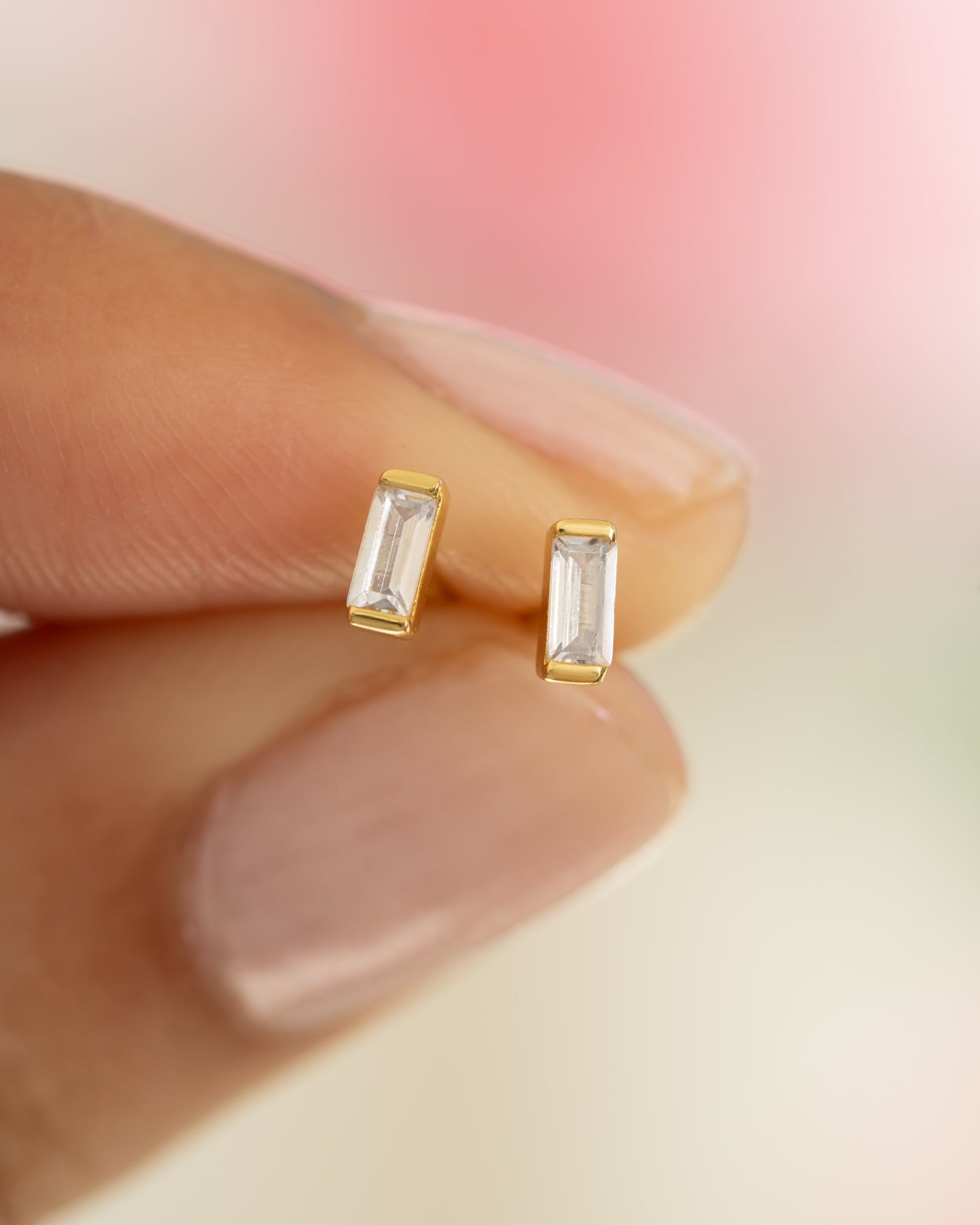 Close-up of white cubic zirconia baguette stud earrings by Sami Jewels, showcasing sparkling gemstone details on gold setting.