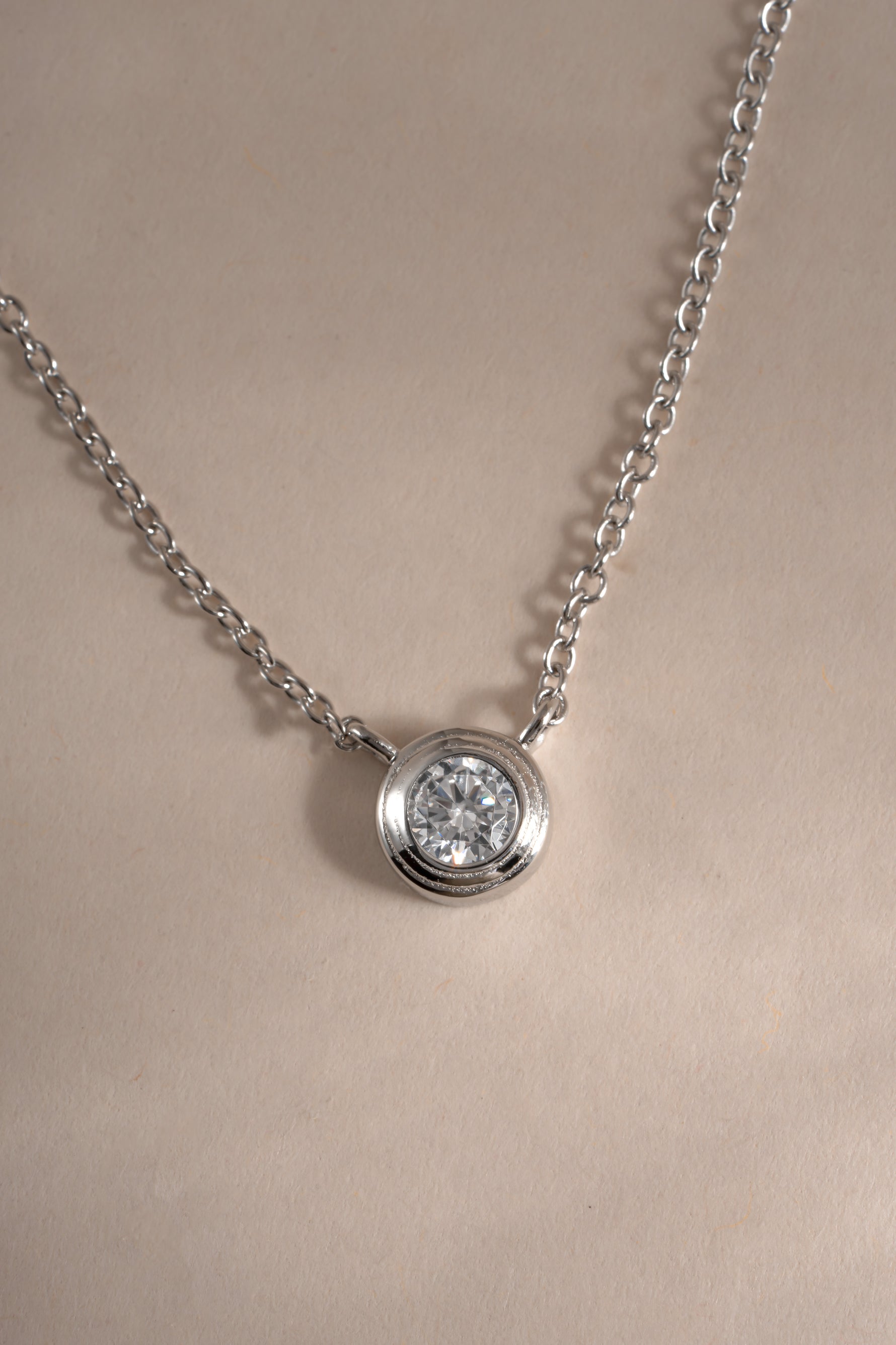 Close-up of Sami Jewels Tiny Bezel Necklace featuring a sterling silver chain with a small diamond bezel pendant.