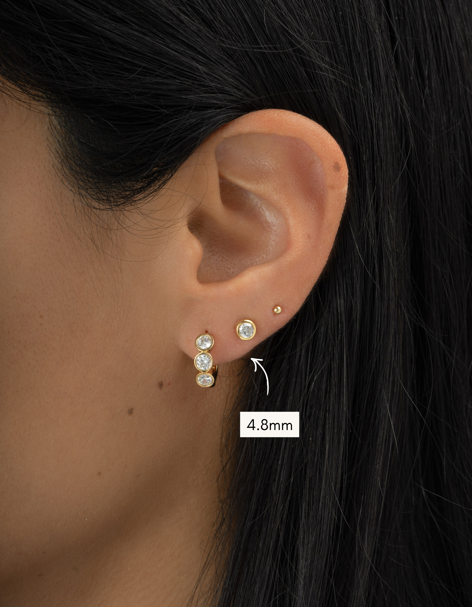 Close-up of an ear wearing a gold earring with a size label indicating 4.8mm.