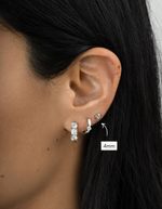 Close-up of an ear wearing two silver earrings with a size label indicating 4mm.