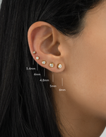 Close-up of an ear with gold earrings and size measurements indicated.
